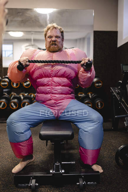 Homme portant un costume rose bodybuilder pratiquant dans la salle de gym — Photo de stock