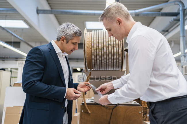 Two businessmen examining product in a factory — Stock Photo