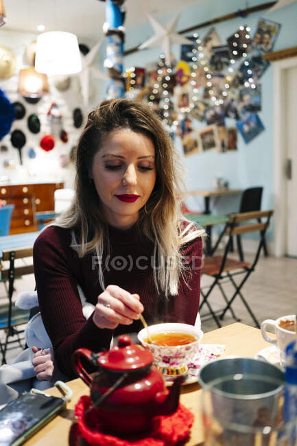 Жінка сидить за столом в кафе з чашкою чаю — стокове фото