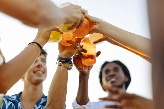 Felices amigos multiétnicos brindando bebidas - foto de stock