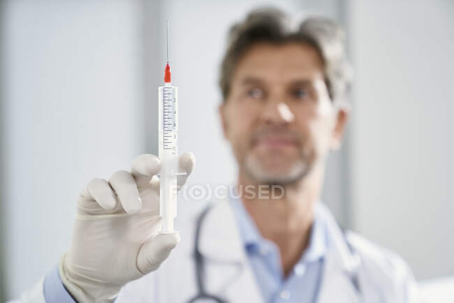 Доктор тримає шприц у своїй медичній практиці — стокове фото