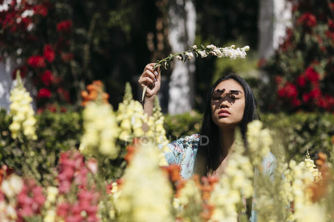 Bella giovane donna che tiene il fiore in un giardino pubblico in primavera — Foto stock
