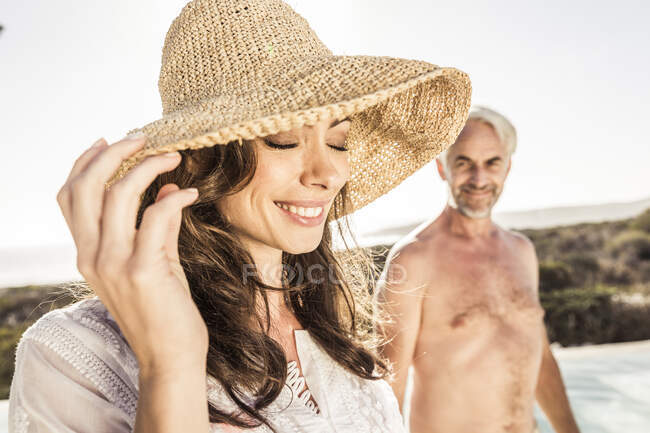 Mulher sorridente usando chapéu de palha na beira da piscina — Fotografia de Stock