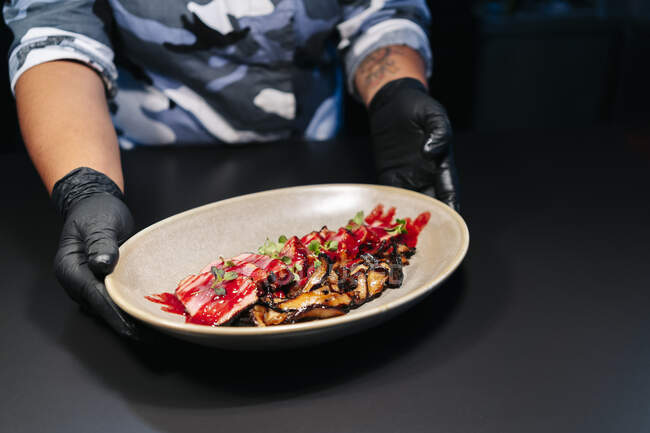 Шеф-повар показывает приготовленное блюдо на столе на кухне ресторана — стоковое фото