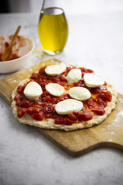 Pizza Margharita demi-faite sur planche à découper — Photo de stock