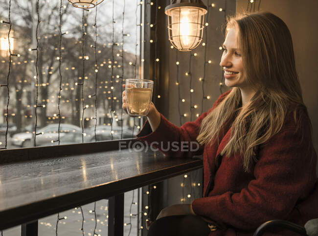 Smiling young woman with cup of tea in a coffee shop — Stock Photo