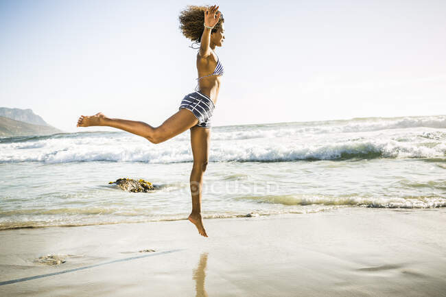 Joyeux jeune femme sautant sur la plage — Photo de stock