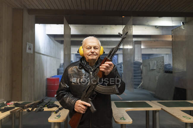 Портрет пожилого человека с пистолетом в тире — стоковое фото