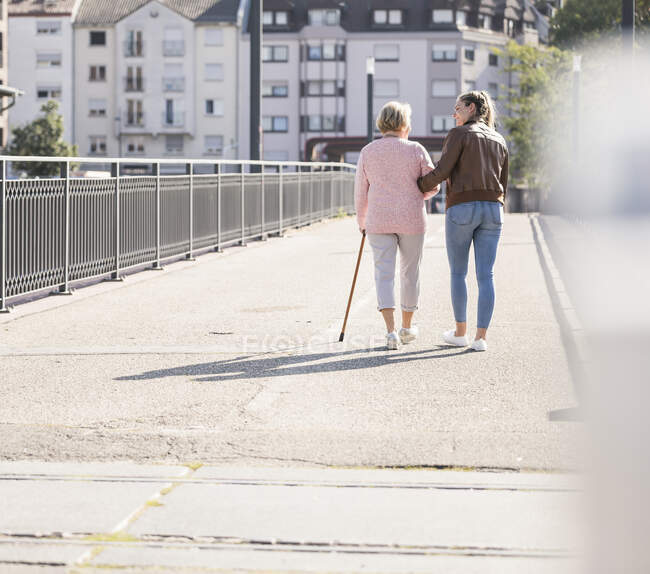 Внучка с бабушкой идут по пешеходному мосту — стоковое фото