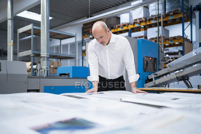 Empresario en una planta de impresión comprobando el producto - foto de stock