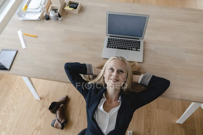 Молодая деловая женщина, у которой перерыв в офисе, лежит на столе — стоковое фото