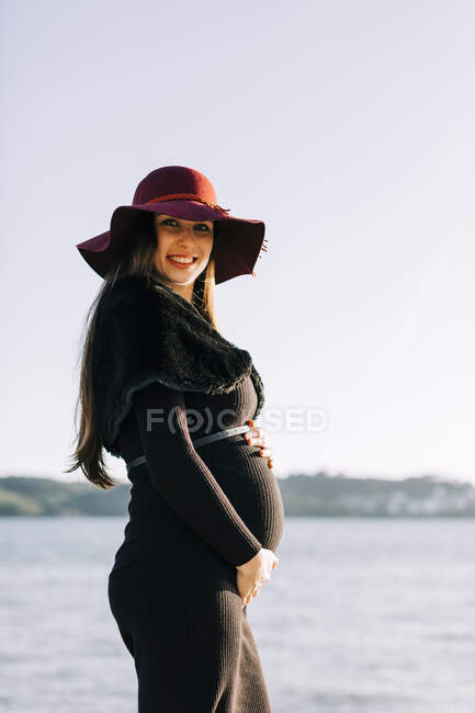 Porträt einer modischen Schwangeren, die am Wasser steht — Stockfoto
