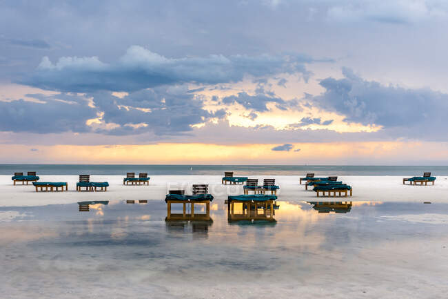 EUA, Flórida, céu nublado sobre cadeiras de convés na praia costeira vazia do Golfo do México ao entardecer — Fotografia de Stock