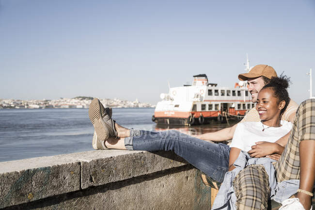 Jovens casais felizes sentados à beira-mar, Lisboa, Portugal — Fotografia de Stock
