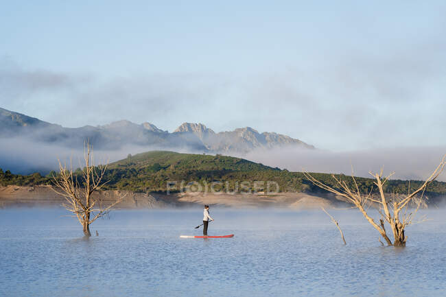 Woman stand up paddle surfing on a lake — Stock Photo