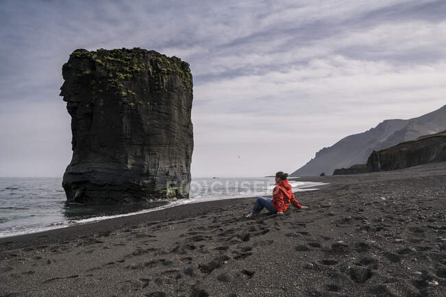 Donna sulla spiaggia di lava nel sud-est dell'Islanda, guardando il mare — Foto stock