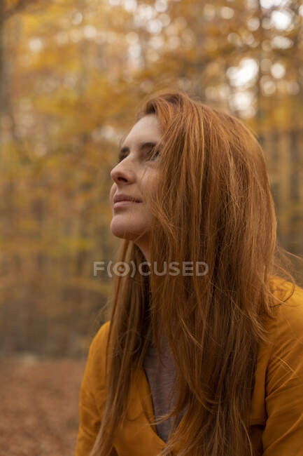 Portrait of redheaded young woman in autumnal forest — Stock Photo