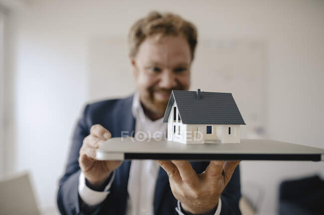 Businessman holding model house in office — Stock Photo