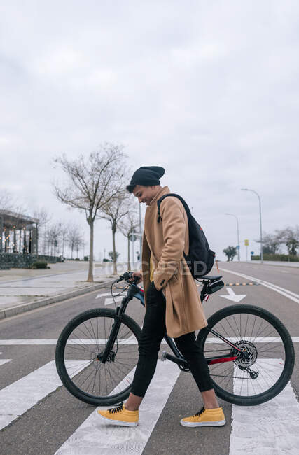 Giovane con bicicletta che attraversa una strada della città — Foto stock