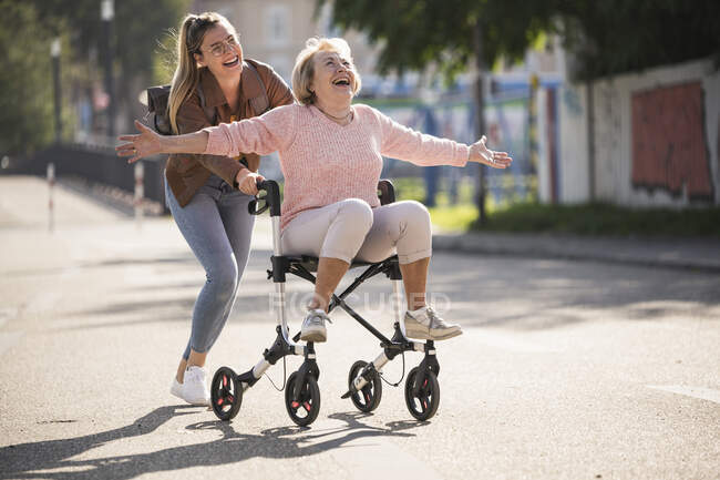 Внучка с бабушкой развлекаются с ходунком на колесах — стоковое фото