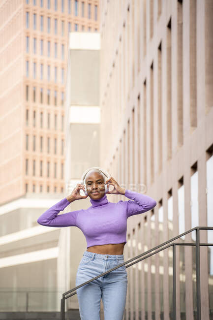 Retrato de mulher de cabelos brancos com fones de ouvido brancos ouvindo música e dançando na cidade — Fotografia de Stock