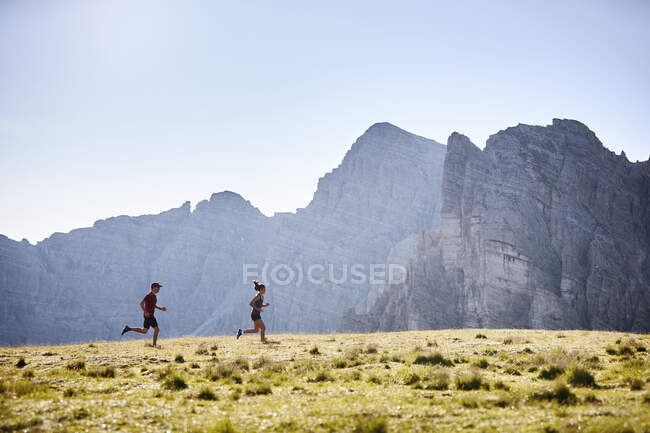 Hombre y mujer corriendo por las montañas - foto de stock