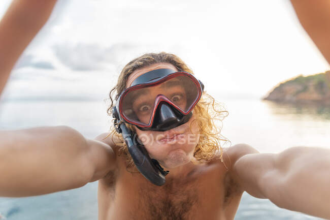 Joven con snorkel haciendo una cara en la playa - foto de stock