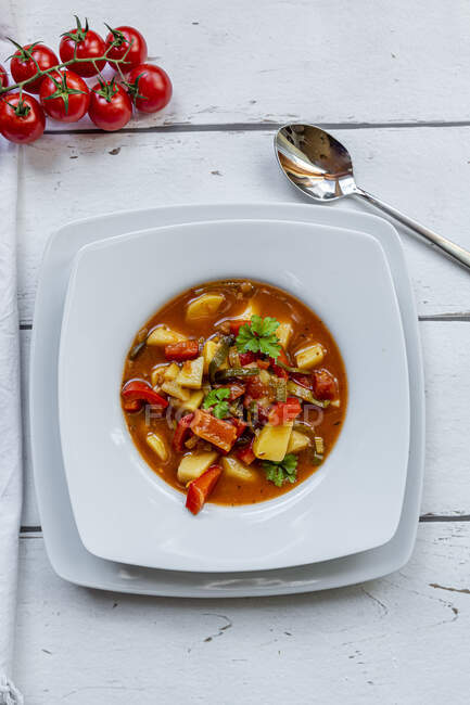 Plate of vegan goulash with potatoes, bell pepper, tomatoes, leek and parsley — Stock Photo