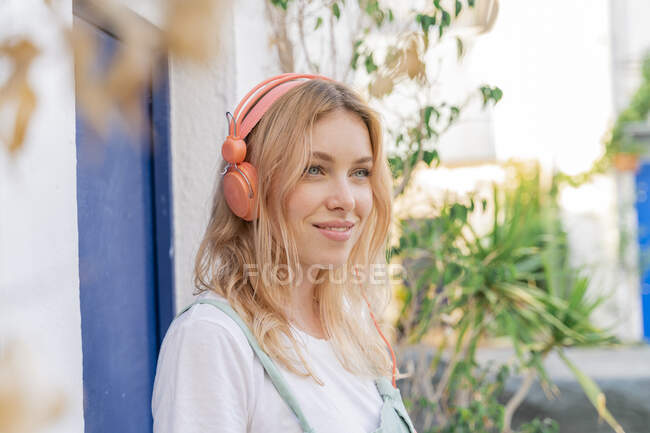 Portrait of young blond woman listening music with headphones — Stock Photo