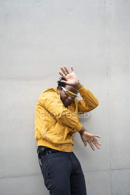 Mature man wearing mirrored sunglasses and yellow jacket raising hands — Stock Photo