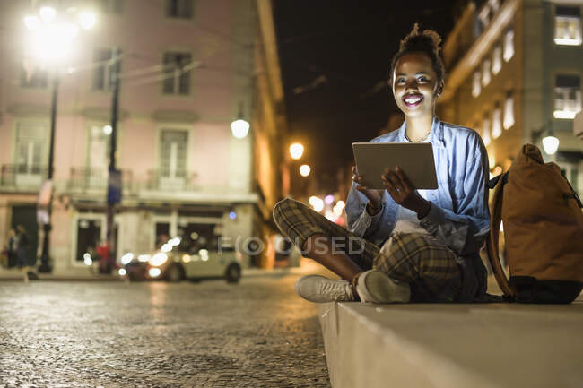 Ritratto di giovane donna felice con tablet digitale in città di notte, Lisbona, Portogallo — Foto stock