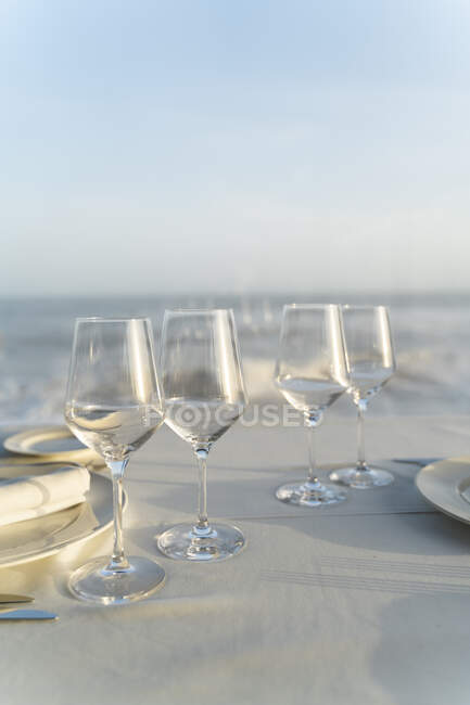 Spain, Empty wineglasses on set restaurant table with sea in background — Stock Photo