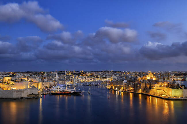 Malta, Birgu, Senglea, beleuchtete Stadt in der Dämmerung und Grand Harbour mit Vittoriosa Yachthafen — Stockfoto