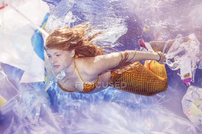 Подростковая русалка ныряет через пластиковые отходы под водой — стоковое фото