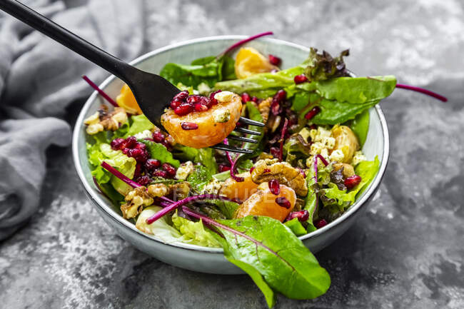 Winter salad with lettuce, tangerines, walnuts, feta and pomegranate seeds — Stock Photo