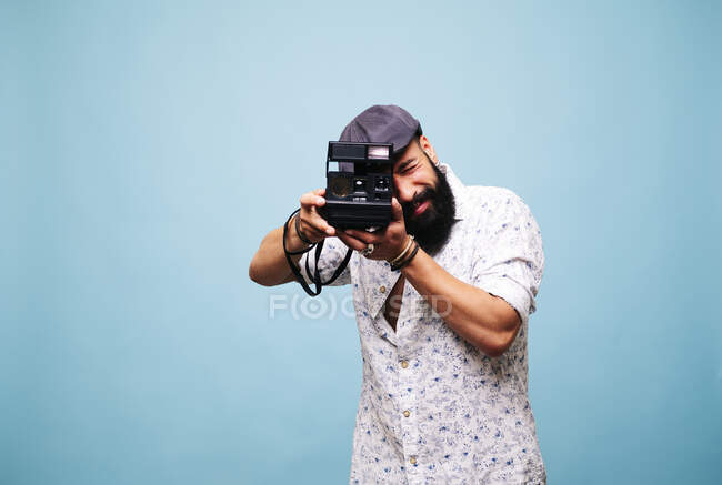 Bearded young man in studio taking picture with instant camera — Stock Photo