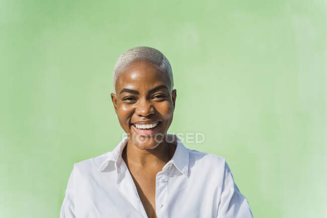 Retrato de la mujer riendo frente a la pared verde - foto de stock