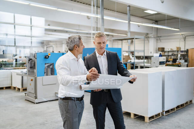 Deux hommes d'affaires discutant d'un plan dans une usine — Photo de stock