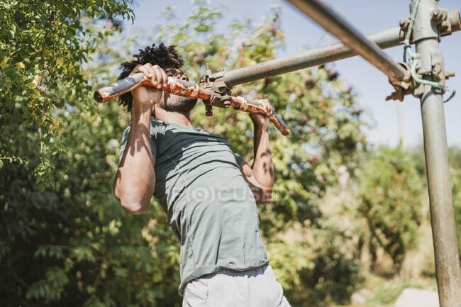 Jeune homme pendant l'entraînement sur un bar dans un parc — Photo de stock