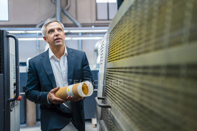 Homme d'affaires dans une usine regardant une machine — Photo de stock