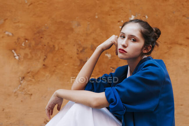 Портрет дівчини - підлітка у блакитній куртці перед коричневою стіною. — стокове фото