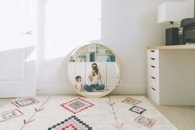 Reflet de la mère prenant une photo d'elle-même et du bébé dans le miroir — Photo de stock