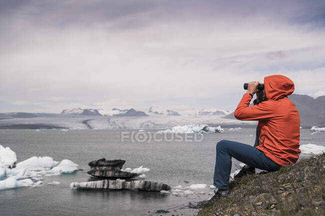 Uomo maturo che guarda Vatnajokull ghiacciaio con binocolo, Islanda — Foto stock