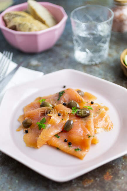 Raw salmon meat with lime, olives and herbs — Stock Photo