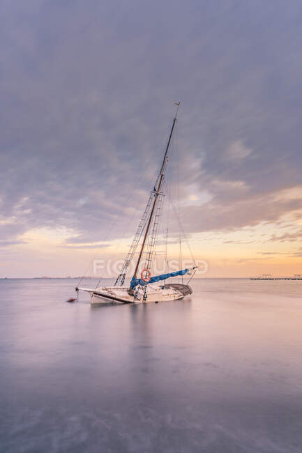 Espagne, Murcie, Santiago de la Ribera, Voilier abandonné sur mer calme au coucher du soleil — Photo de stock