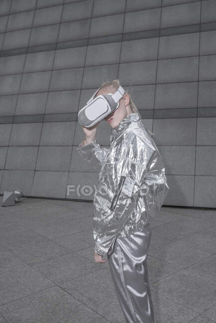 Ragazza in abito argentato. guardando attraverso gli occhiali VR nella città futuristica — Foto stock