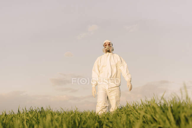 Hombre con traje protector y máscara en un campo - foto de stock