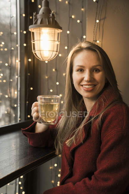 Портрет усмішки молодої жінки зі склянкою чаю в кав 