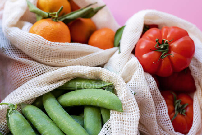 Sacs en mesh réutilisables respectueux de l'environnement avec pois verts frais, tomates et clémentines — Photo de stock