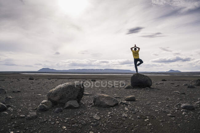 Uomo maturo in equilibrio su una gamba su una roccia negli altopiani vulcanici dell'Islanda — Foto stock